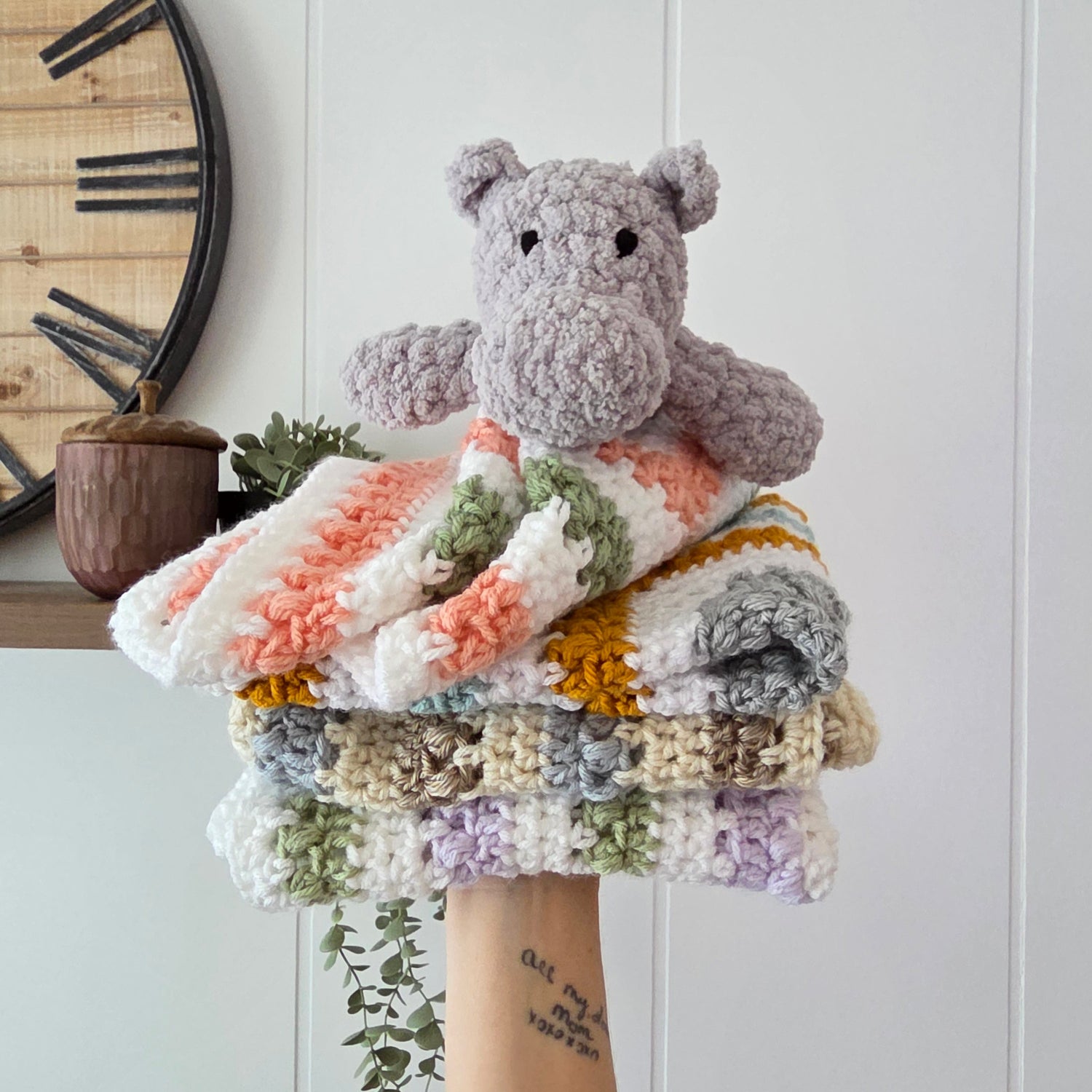 Collection of colorful crocheted scrunchies on a white surface with a wooden clock in the background.
